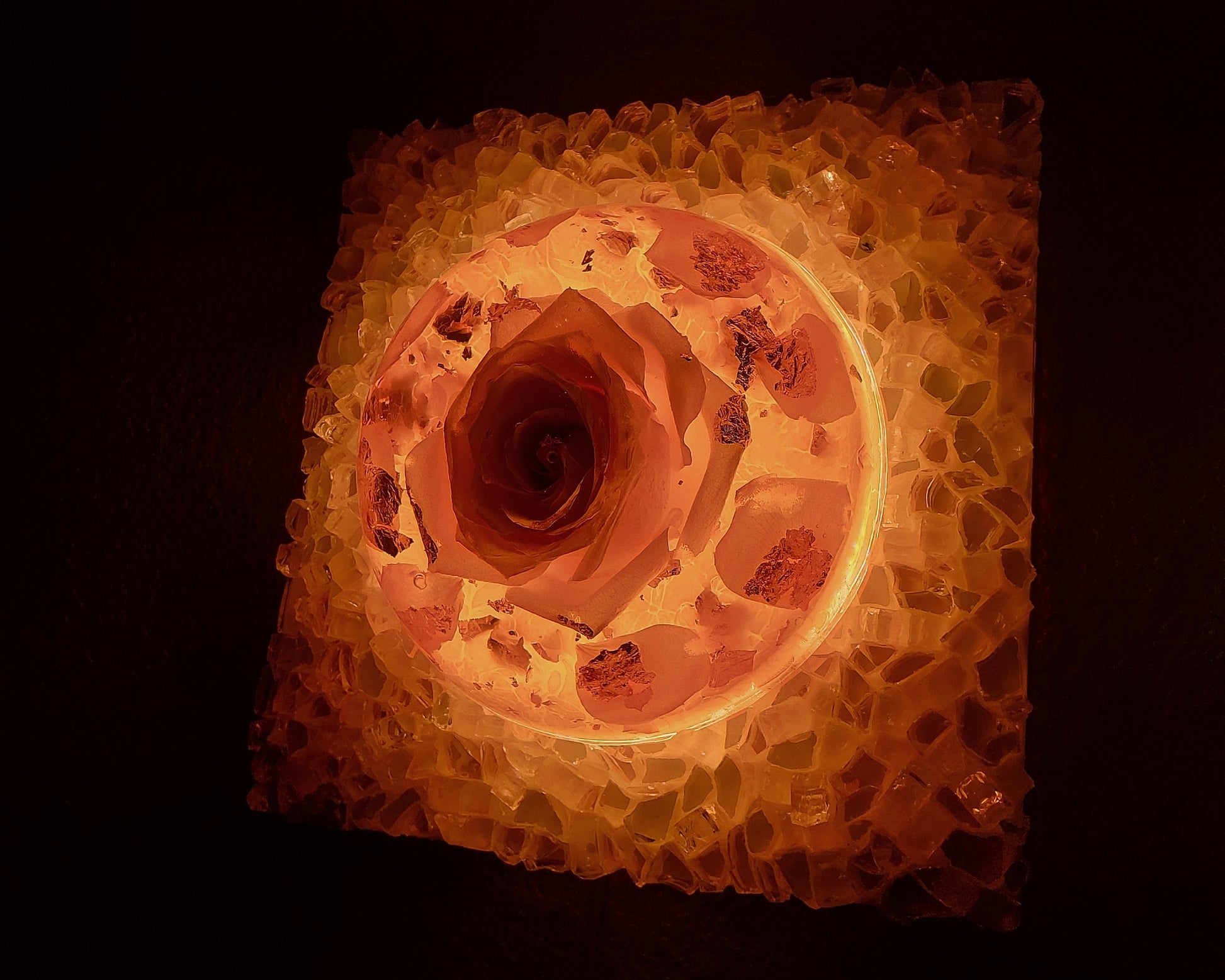Square light fixture with a textured surface and warm glow on a dark background